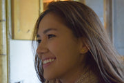 Woman with a side profile, wearing gold earrings, indoors.
