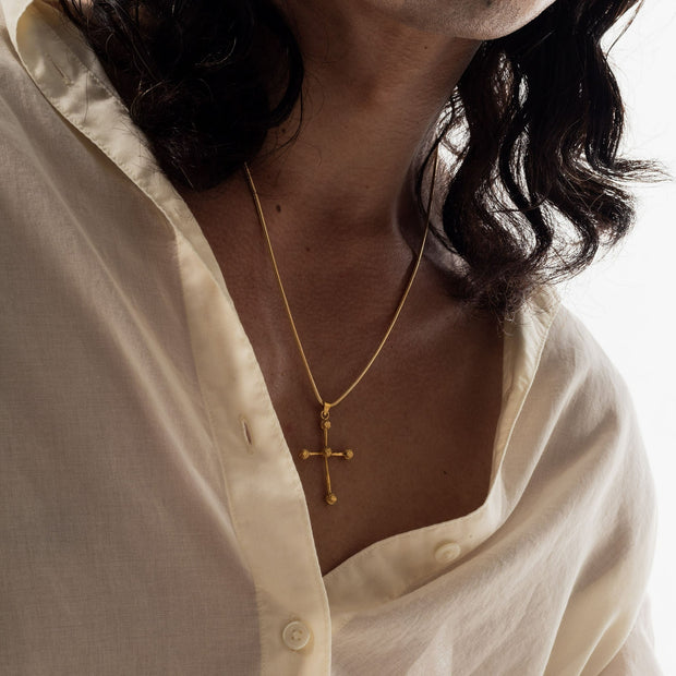 Gold cross pendant necklace worn