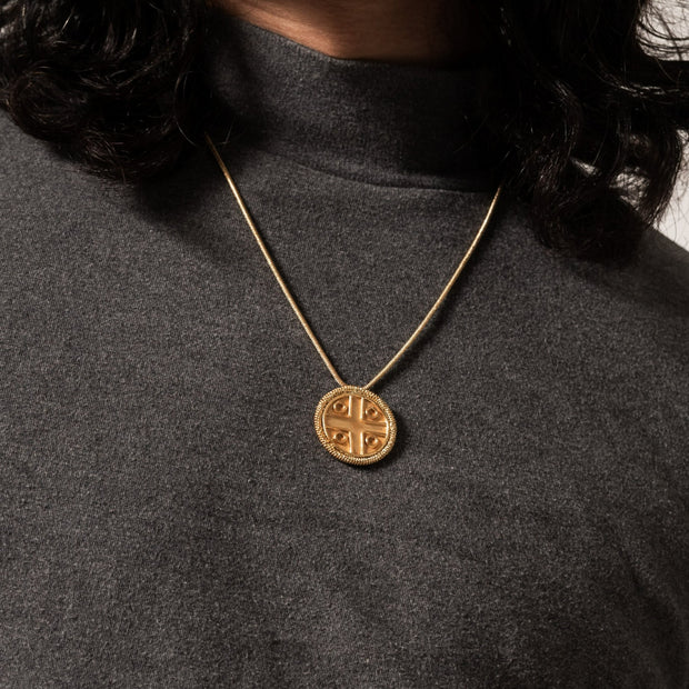 Gold pendant necklace worn with gray turtle neck